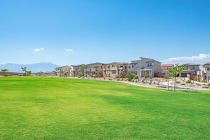 A residential area with multiple houses, a well-maintained lawn, and a clear sky. - Modern Desert Retreat 3BR Home w/ Community Pool (Palm Desert)