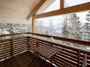 A wooden balcony with a table and chairs, overlooking a snowy mountainous landscape. - Cabin in Turrach With Sauna and Wi-fi (Stadl-Predlitz)