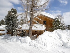 Eine Holzhütte mit schneebedecktem Dach und umliegenden Schneewehen.