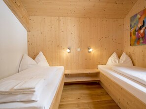 Ein Holzhüttenraum mit zwei Betten, Holzboden und zwei Wandleuchten.