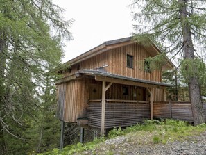 Une cabane en bois avec un porche, entourée d’arbres.