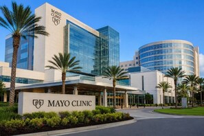 En bygning fra Mayo Clinic med en moderne glasfacade, palmer og en klar blå himmel.