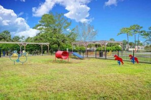 Ein Spielplatz mit Rutsche, Schaukeln und einer roten Kletterkonstruktion.