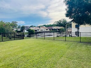 A fenced yard with a grassy area and a row of houses in the background. - Jax Beach Haven 4 bd/Movie Room/Dinning/ Downtown (Jacksonville)