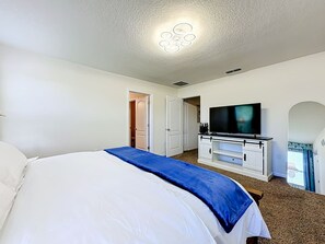 Ein Hotelzimmer mit einem Bett, einem Fernseher, einem weißen Schrank und einer Tür zu einem weiteren Raum.