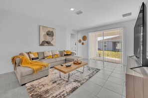 A modern living room with a sectional sofa, a coffee table, and a television. - Extended Stay Winter haven, Eagle Lake, & Lakeland (Eagle Lake)
