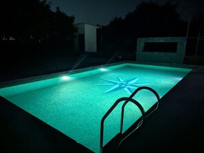 Una piscina con un diseño en forma de estrella en el suelo, rodeada de un ambiente oscuro.