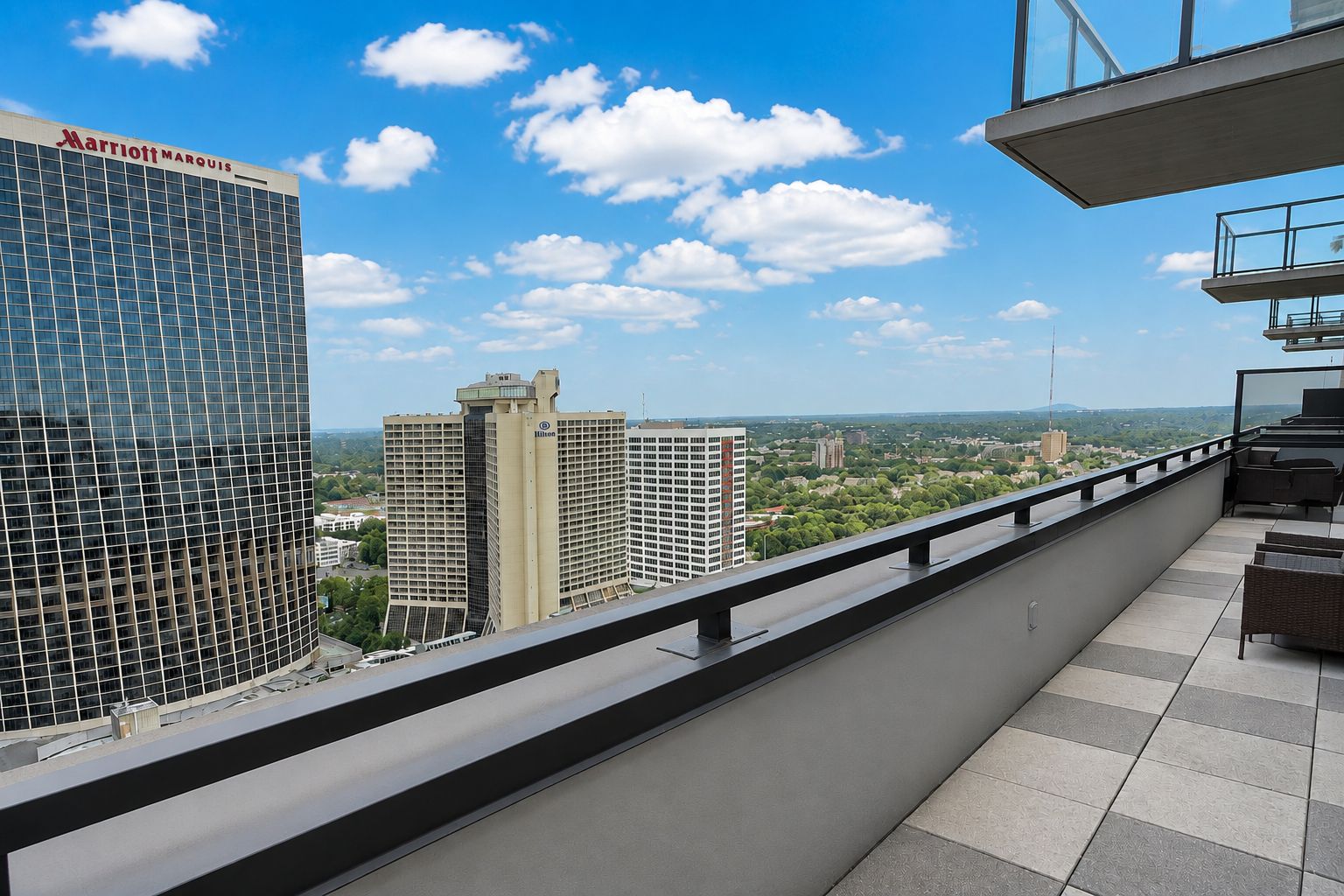 A hotel balcony with a view of surrounding buildings and a clear sky.