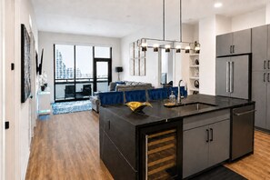 A modern kitchen with a central island, built-in appliances, and a large window overlooking a cityscape. - Downtown Penthouse | 2 King BD/ 2 BA| Year-round Pool | Balcony |Walk Everywhere (Atlanta)