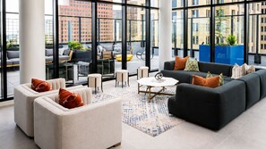 A modern lounge area with sofas, chairs, and a coffee table, large windows offering city views. - Downtown Penthouse | 2 King BD/ 2 BA| Year-round Pool | Balcony |Walk Everywhere (Atlanta)