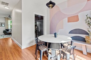 Ein moderner Essbereich mit einem runden Tisch, Stühlen und einem Kühlschrank im Hintergrund.