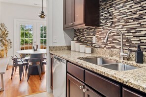 Eine moderne Küche mit Granit Arbeitsplatten, einer Edelstahl-Spüle und dunklen Holzschränken.