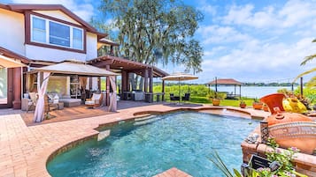 A swimming pool with a hot tub, outdoor furniture, and a covered patio area.