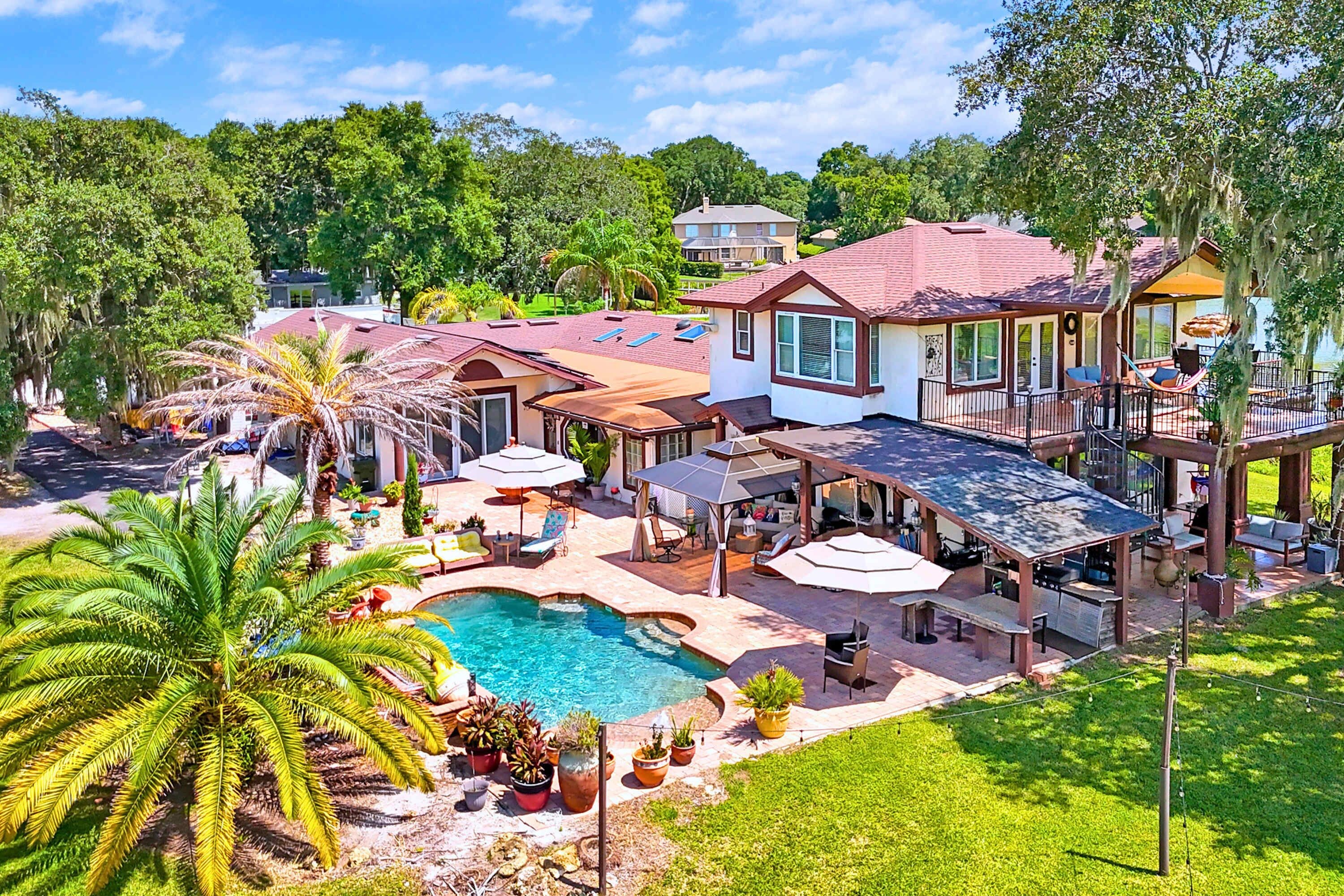 A residential property with a swimming pool, outdoor seating, and a covered patio area.