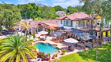A residential property with a swimming pool, outdoor seating, and a covered patio area.
