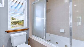 A bathroom with a toilet, a shower enclosure, and a window with blinds.