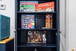 Una estantería con diversos juegos de mesa, incluyendo Monopoly, Scrabble, Connect4, Jenga y Clue.