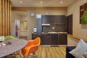 Una cocina moderna con gabinetes oscuros, horno empotrado y microondas. Hay una mesa de comedor con una silla y una alfombra pequeña.