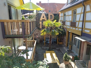 A courtyard with a wooden table and chairs, a yellow umbrella, and a large 'A' sign. - Maisonette Apartment - The Dovecote - Ad1716 (Marktheidenfeld)