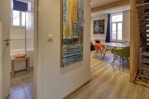Un pasillo con un banco de madera, un cuadro y un comedor con sillas y una mesa.