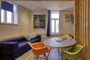 Una habitación con un sofá, una mesa redonda y dos sillas.