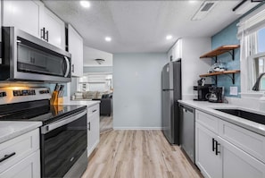 A modern kitchen with a microwave, oven, and refrigerator. - Sunny Coastal Cottage Near the Beach (North Myrtle Beach)