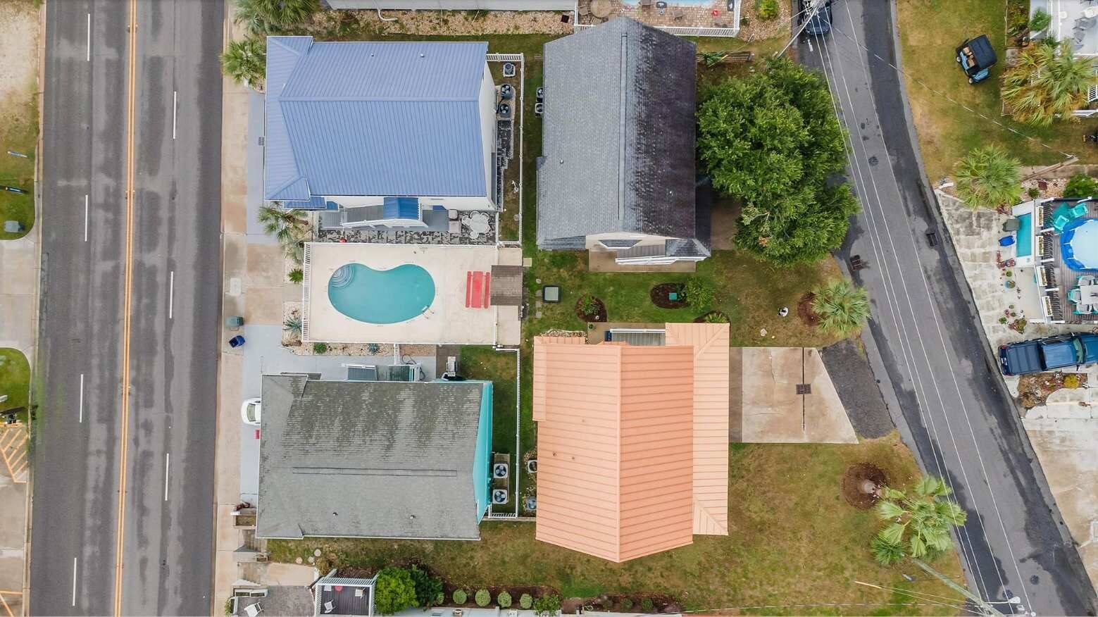 Vista aérea de una propiedad residencial con piscina, garaje y una casa grande con techo inclinado.