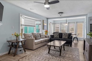 A living room with a sofa, coffee table, and a ceiling fan. - Sunny Coastal Cottage Near the Beach (North Myrtle Beach)