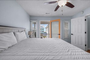 A bedroom with a bed, a ceiling fan, and a view of the outside. - Sunny Coastal Cottage Near the Beach (North Myrtle Beach)