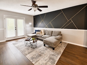 A living room with a sectional sofa, a coffee table, and a ceiling fan. - Magnolia Haus Hoover | King + Queen Stay E2 (Hoover)
