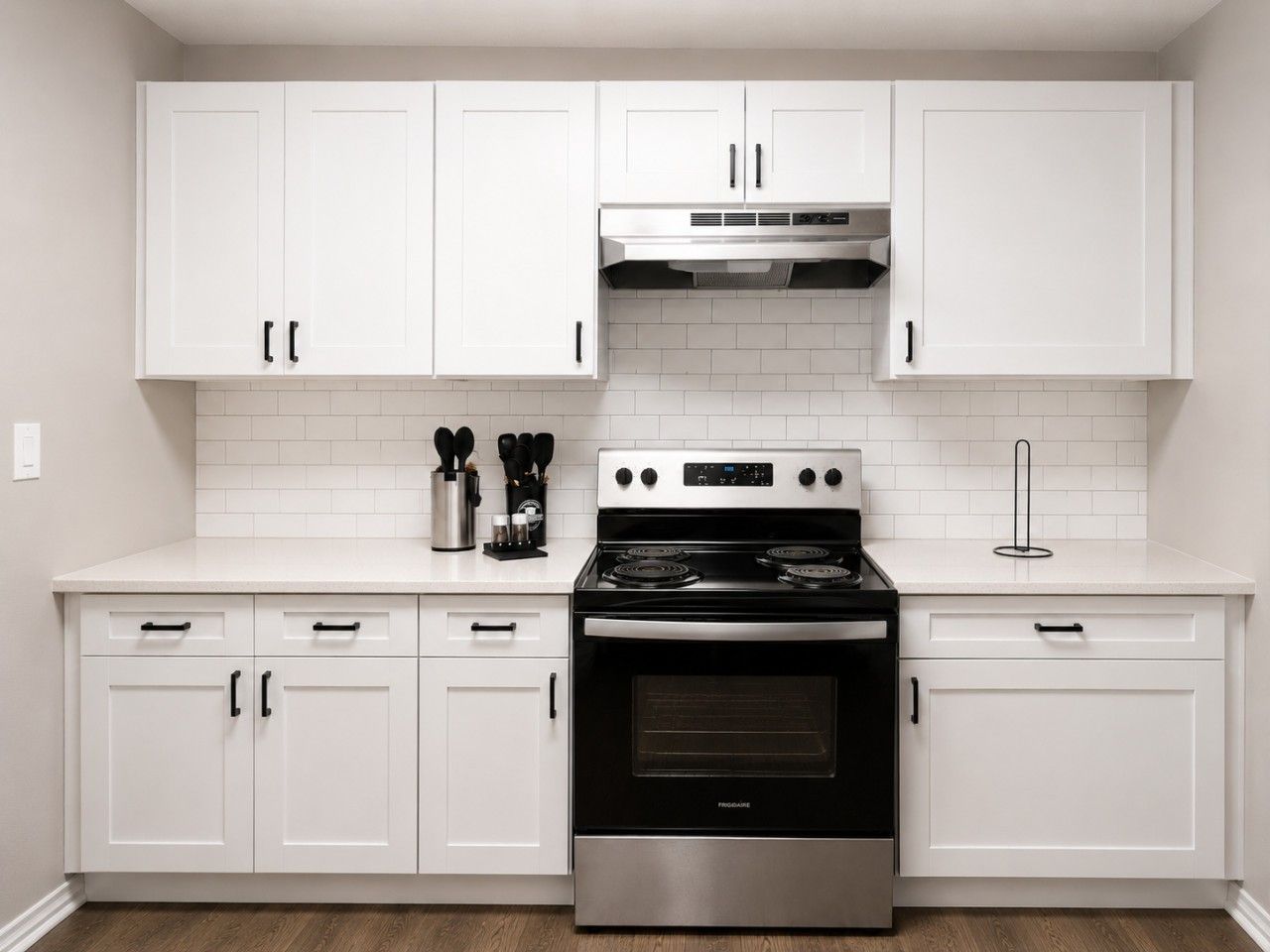 A kitchen with white cabinets, a stainless steel stove, and a tiled backsplash.