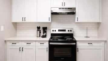 A kitchen with white cabinets, a stainless steel stove, and a tiled backsplash.