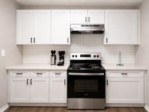 A kitchen with white cabinets, a stainless steel stove, and a tiled backsplash.