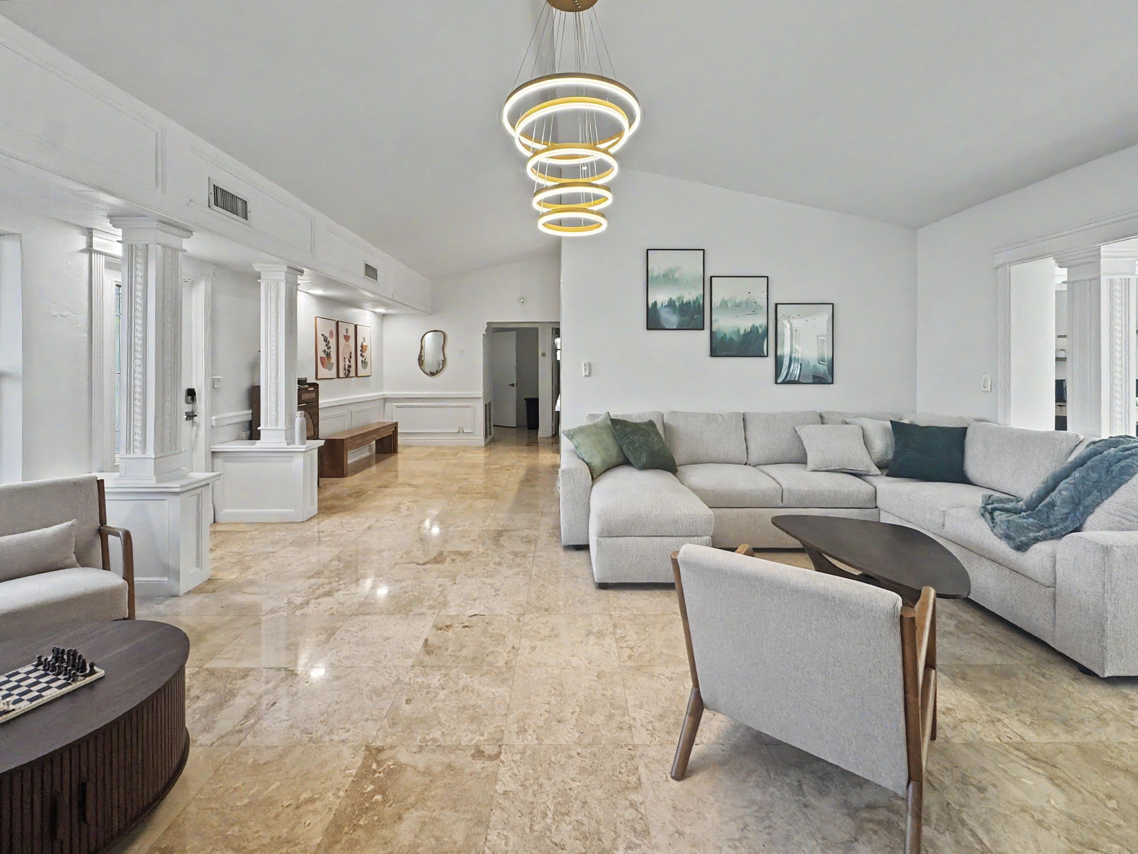A spacious living area with a large sectional sofa, a coffee table, and a chessboard.