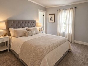 Ein Schlafzimmer mit einem großen Bett, einem Nachttisch, einer Lampe und einem gerahmten Bild an der Wand.