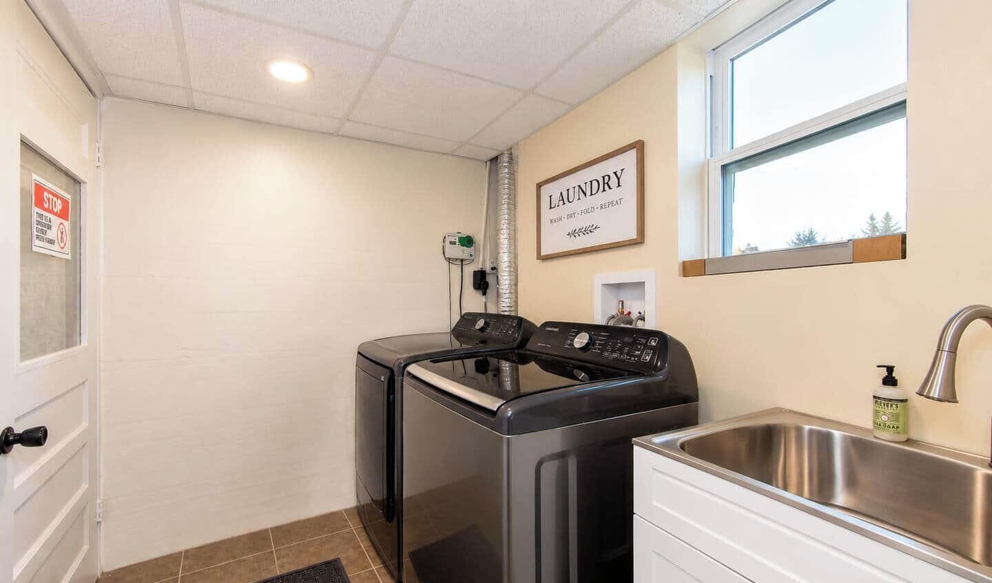 A laundry room with a washing machine, dryer, and a sink with a soap dispenser.