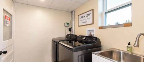 A laundry room with a washing machine, dryer, and a sink with a soap dispenser.