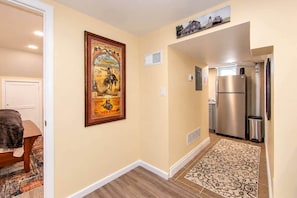 A hallway with a framed historical poster, a kitchen area with a refrigerator, and a patterned rug. - Cheyenne Plains 2 bedroom (Cheyenne)