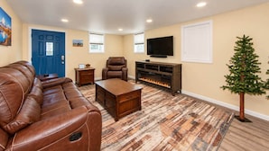 A living room with a leather sofa, a coffee table, a fireplace, a television, and a small Christmas tree. - Cheyenne Plains 2 bedroom (Cheyenne)