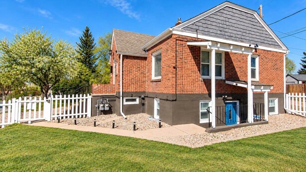 A two-story brick house with a white picket fence, a blue door, and a well-maintained lawn. - Cheyenne Plains 2 bedroom (Cheyenne)
