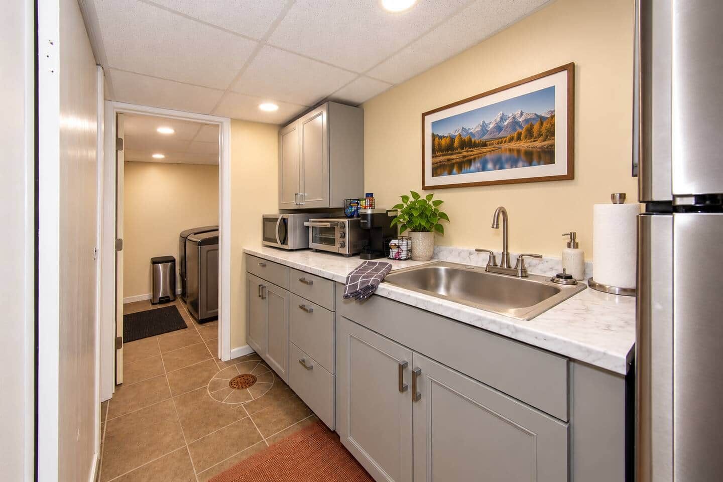 A compact kitchen with a stainless steel refrigerator, a sink, and a microwave.