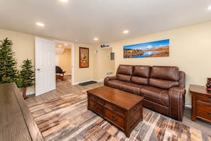 A living room with a brown leather sofa, a wooden coffee table, and a painting on the wall. - Cheyenne Plains 2 bedroom (Cheyenne)