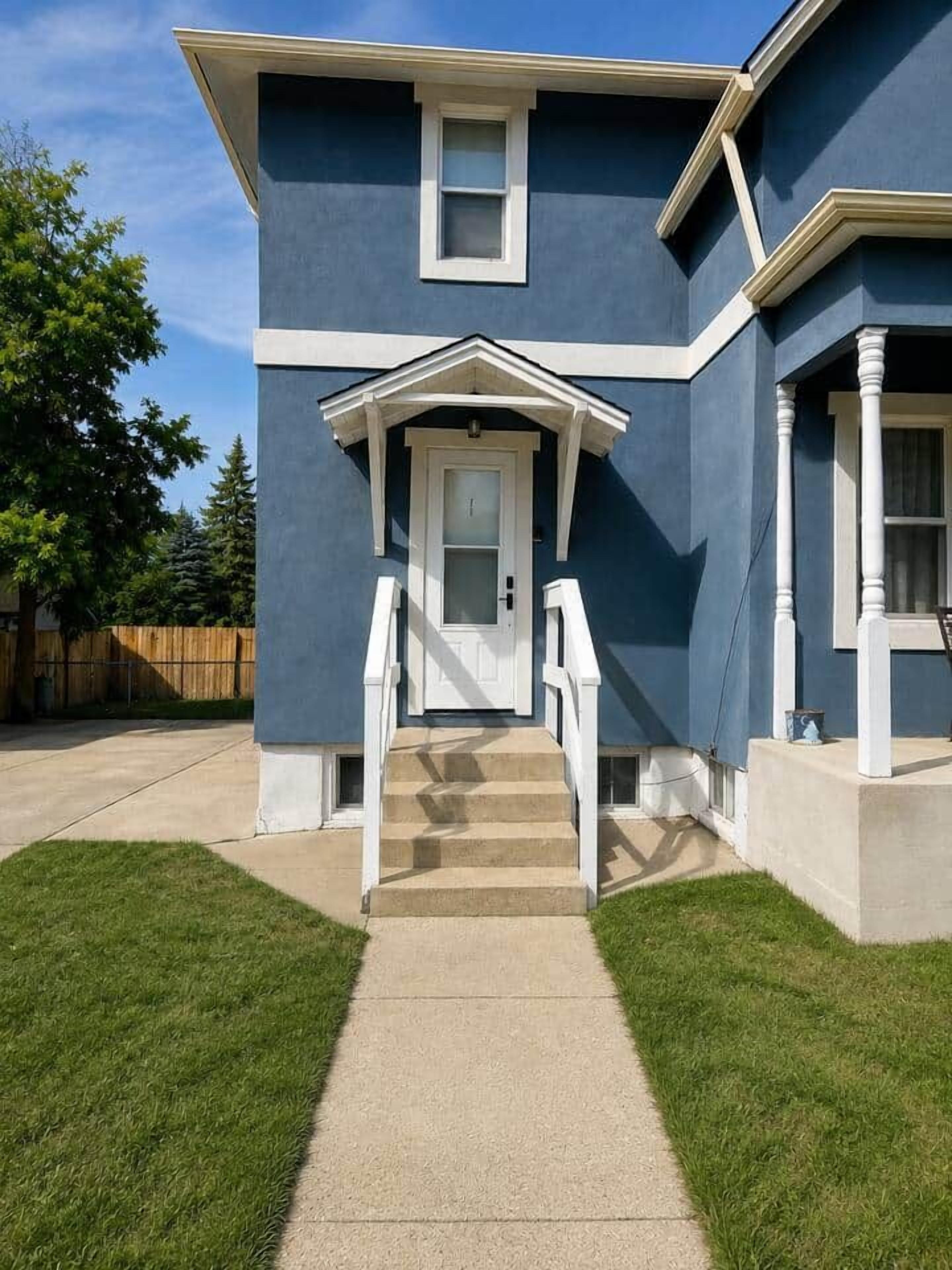A two-story house with a front porch, a door, and a set of stairs leading to the entrance.