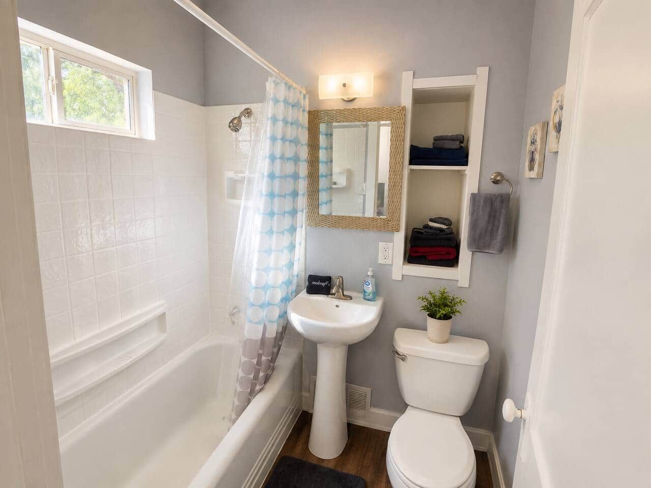 Et badeværelse med badekar, vask, toilet og et vindue.