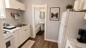 Cocina compacta con muebles blancos, horno empotrado, pileta y refrigerador.