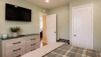 A bedroom with a bed, a dresser, a television, and a door.