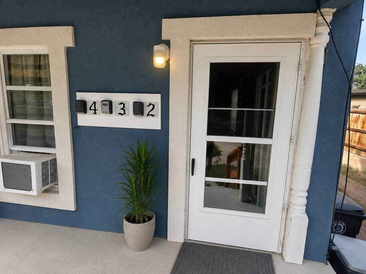 Une maison avec le numéro « 432 » sur le mur, une porte avec des panneaux de verre et une plante en pot.