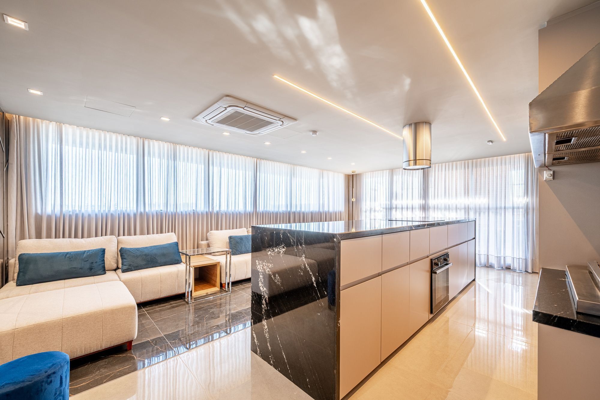 Cozinha moderna com ilha central, eletrodomésticos embutidos e bancada elegante.