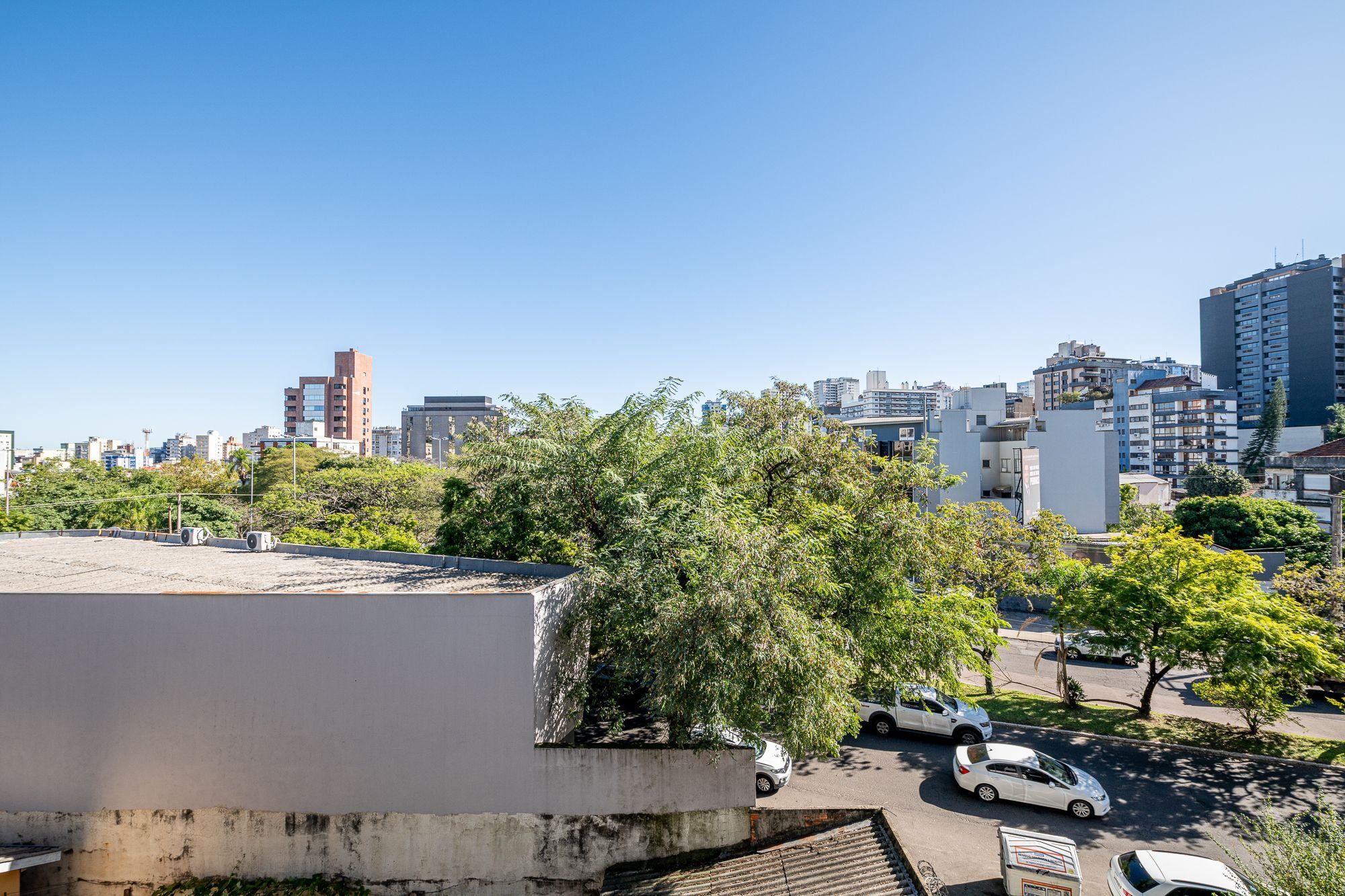 Un paisaje urbano con edificios modernos, cielo despejado y un estacionamiento con coches.
