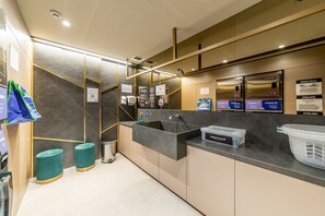 Un baño moderno con lavamanos, espejo y artículos de aseo.
